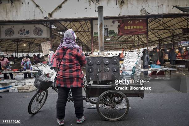Woman stands next to a tricycle outside a market in Penglai, Shandong Province, China, on Thursday, Feb. 16, 2017. China's 1.4 billion people are...