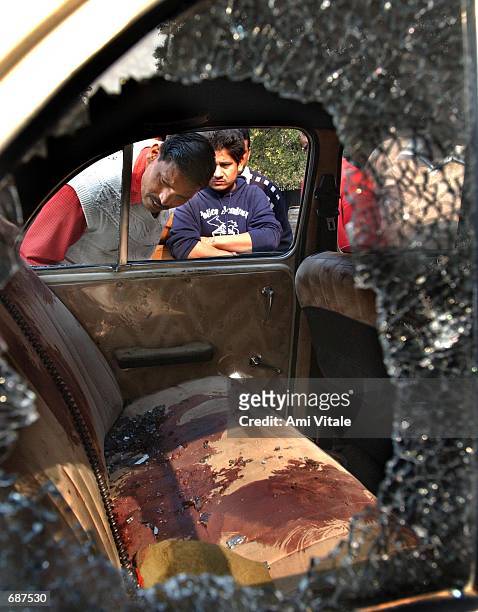 Indians look inside the shattered windows of a blood soaked car used in the Indian vice presidents convoy outside the Parliament House December 14,...