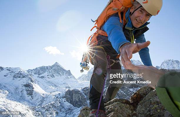 mountaineer extends helping hand to teammate - hände greifen stock-fotos und bilder