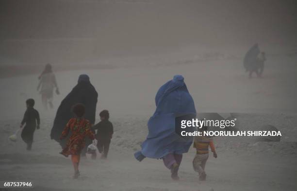 In this photograph taken on May 23 Afghan women with their children walk through dense fog on the outskirts of Jalalabad. / AFP PHOTO / NOORULLAH...