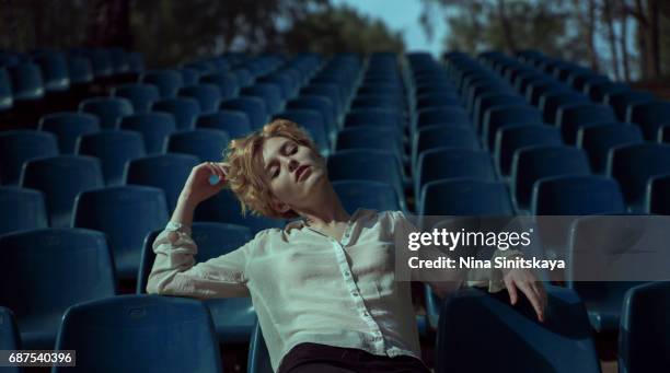 woman with short hair hanging out at blue stadium seats - brustwarze stock-fotos und bilder