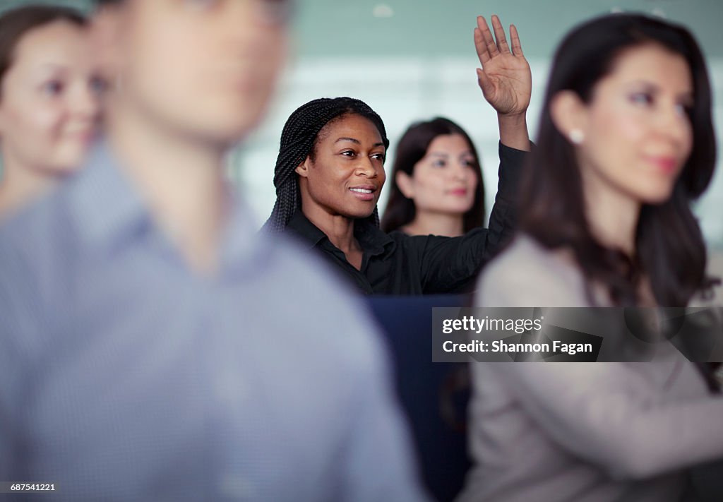 Woman raising hand in group seminar workshop