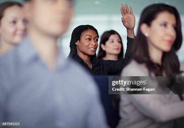 woman raising hand in group seminar workshop - raised hand stock pictures, royalty-free photos & images