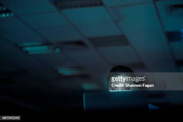 man looking at laptop computer in office at night - working late stockfoto's en -beelden