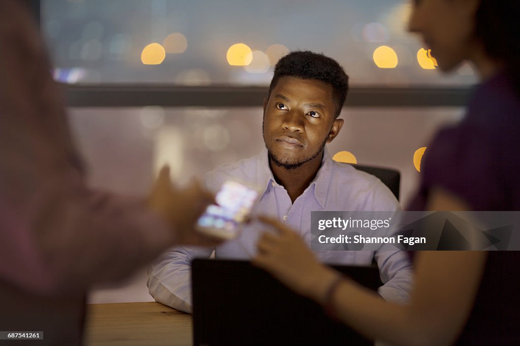 Man watching office colleagues discuss plans