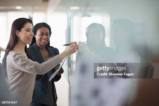 women working on office dry erase board together - woman coach stock pictures, royalty-free photos & images