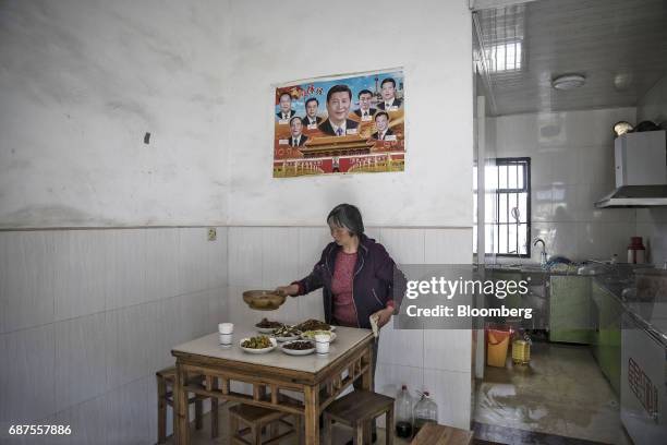 Farmer sets a table for lunch under a poster featuring Xi Jinping, China's president, and other members of the politburo standing committee at a farm...