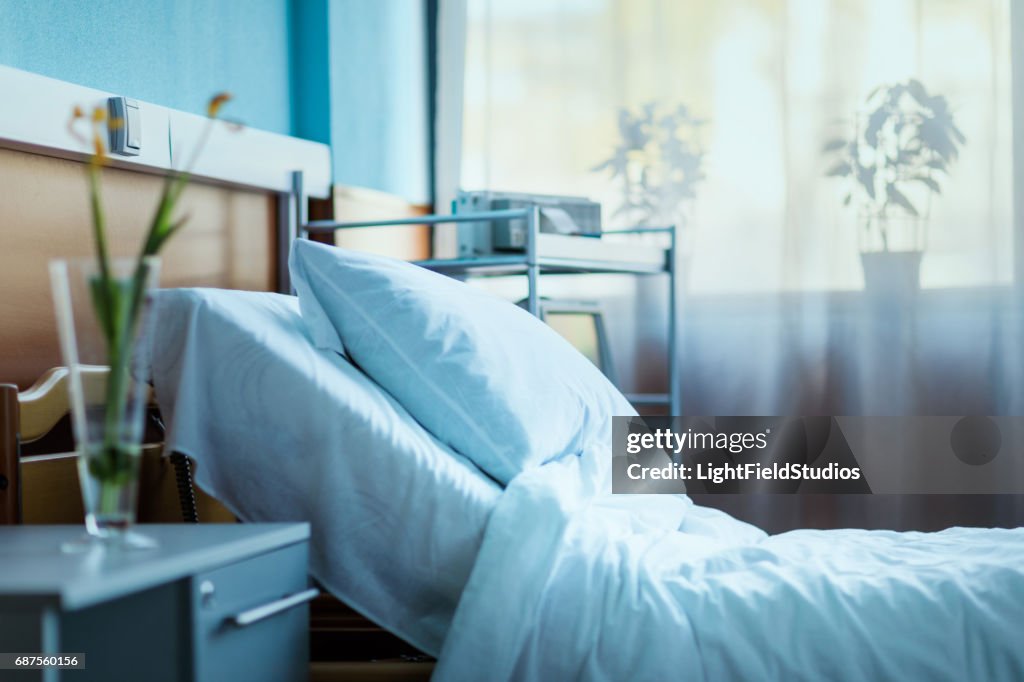 Side view of empty hospital bed in clinic chamber