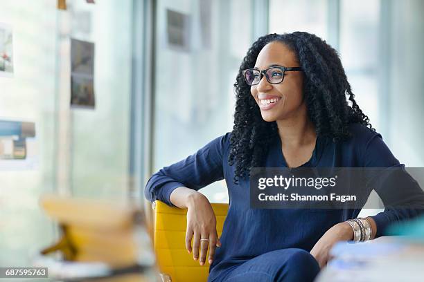 woman looking sideways to window in design office - frau modern jung business stock-fotos und bilder