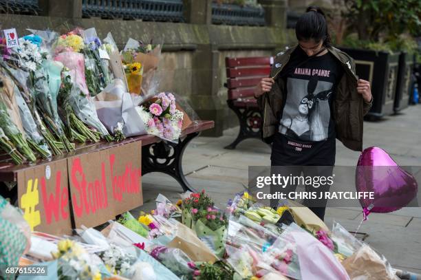 Girl, wearing a t-shirt from Ariana Grande's Dangerous Woman Tour, poses for a photograph alongside flowers in Albert Square in Manchester, northwest...