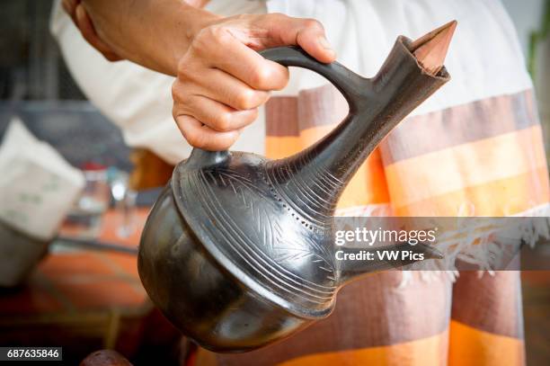 Hands pouring Ethiopian coffee out of traditional jebena..