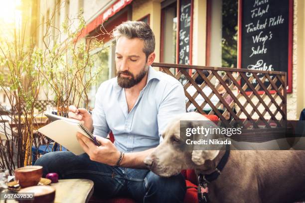 young hipster man with dog sketching in street cafe - dog pad stock pictures, royalty-free photos & images