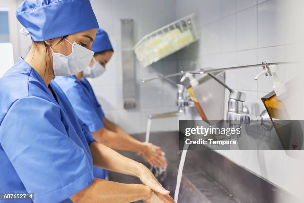 équipe de chirurgiens dans la salle d’opération dans un hôpital. - se frotter les mains photos et images de collection
