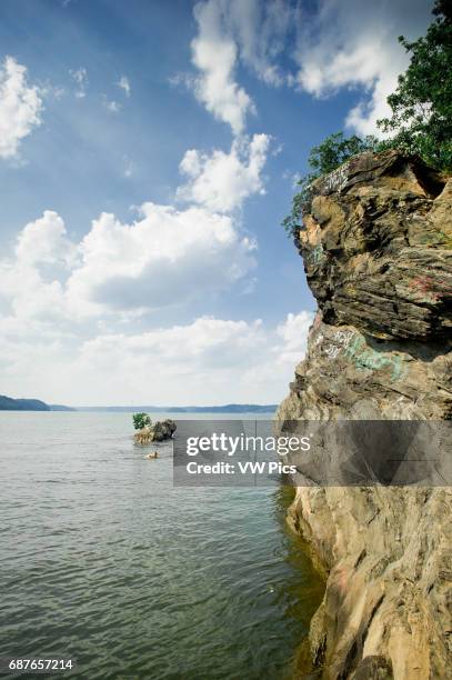 Cliff on the water under rays of sun peaking out of clouds of big blue sky in Maryland near Mason Dixon line.