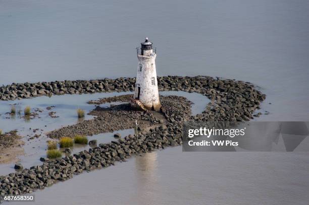 Cockpur Island Lighthouse, an old style brick lighthouse surrounded by water and rock, Tybee Island, Georgia, USA.