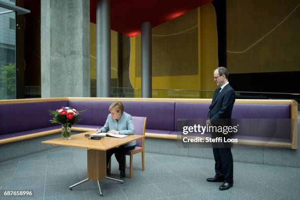 German Chancellor Angela Merkel writes in a book of condolence next to Britains Ambassador to Germany Sir Sebastian Wood at the British embassy on...