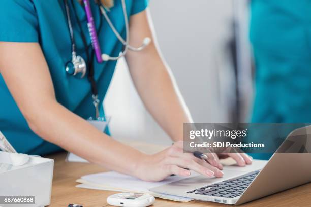 vertrouwen verpleegkundige maakt gebruik van laptop in spreekkamer - spoedeisende geneeskunde stockfoto's en -beelden