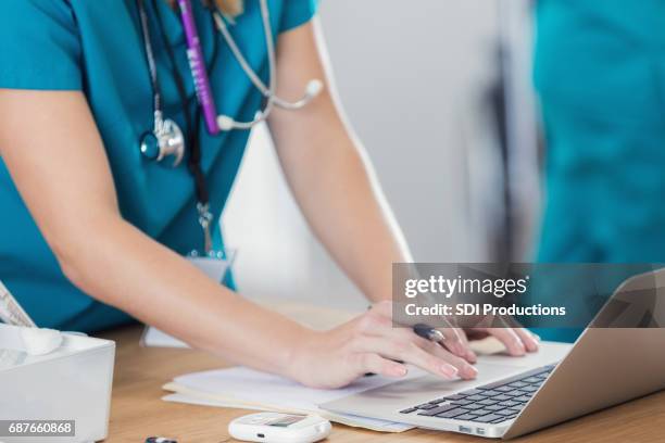 confident nurse uses laptop in doctor's office - emergency medicine stock pictures, royalty-free photos & images