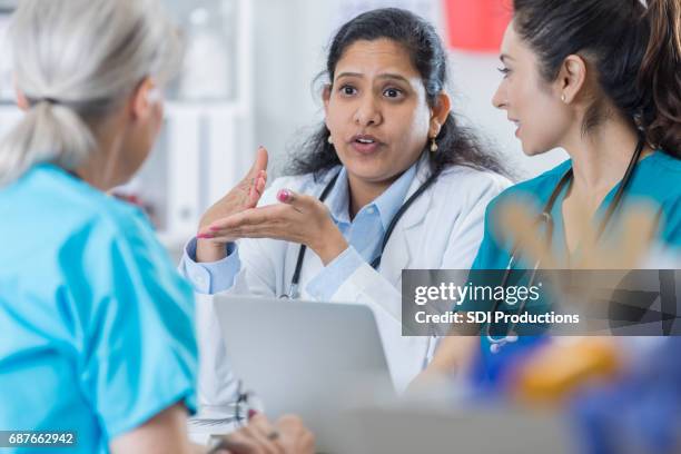 indian doctor discusses something with medical staff - female doctors group stock pictures, royalty-free photos & images