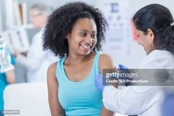doctor places bandage on patient's arm - injection girl stock pictures, royalty-free photos & images