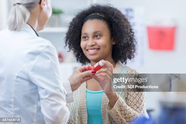 afro americana adolescente aprende a utilizar inhalador - asmático fotografías e imágenes de stock