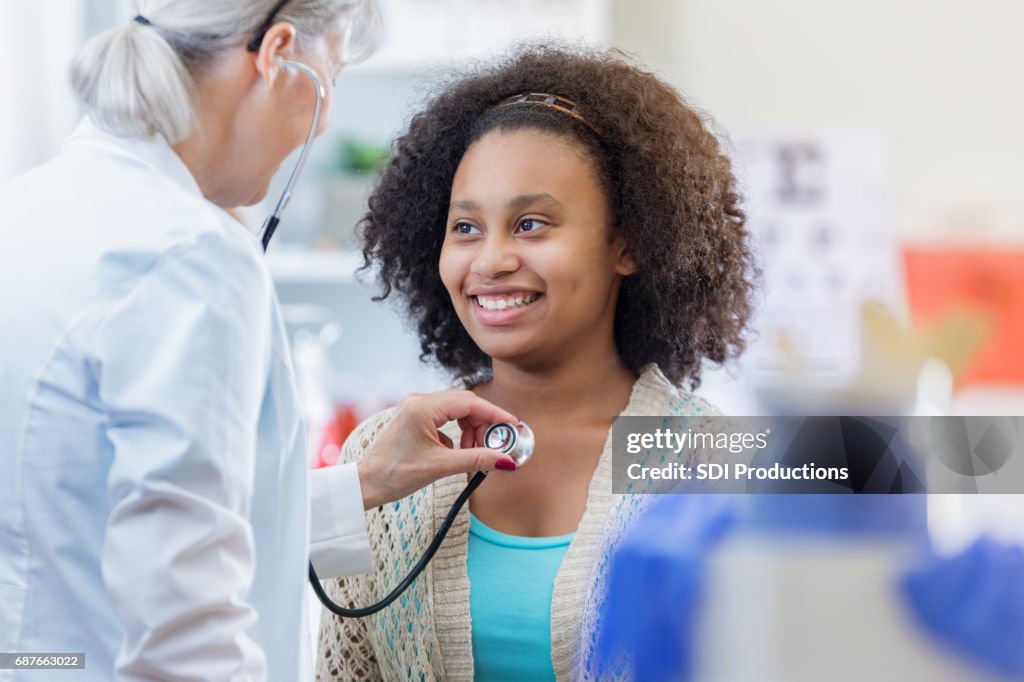 Physician listens to teenage girls heartbeat