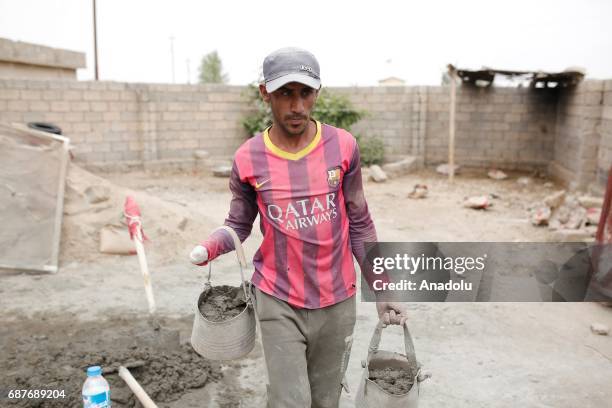 Muhammed, one of the two siblings who was accused of theft and whose right hand was cut off by Daesh, carries cement buckets in Ninova, Iraq on May...