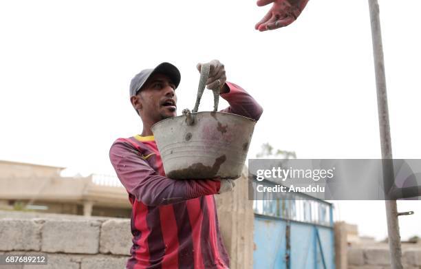 Muhammed, one of the two siblings who was accused of theft and whose right hand was cut off by Daesh, carries a cement bucket in Ninova, Iraq on May...