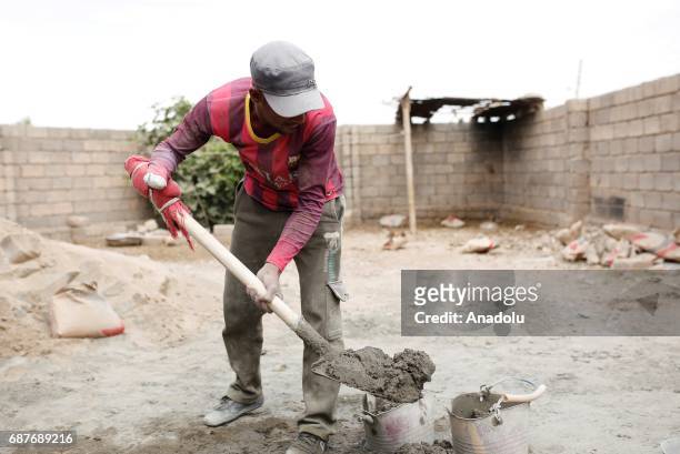 Muhammed, one of the two siblings who was accused of theft and whose right hand was cut off by Daesh, mixes cement in Ninova, Iraq on May 23, 2017....