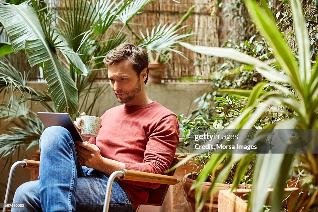 Man using digital tablet while having coffee