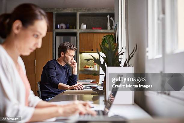 mid adult business couple working at desk - telecommuting couple stock pictures, royalty-free photos & images