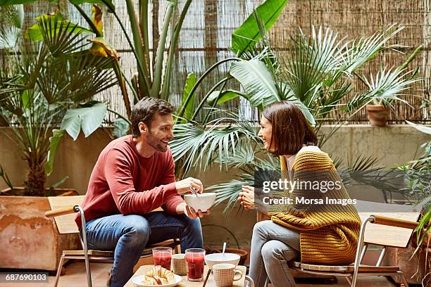 man looking at woman while having breakfast - garden talking photos et images de collection