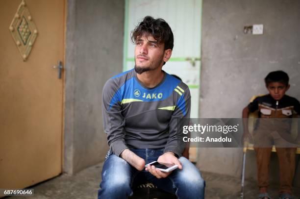 Azad, one of the two siblings who was accused of theft and whose right hand was cut off by Daesh, plays with a dog in Ninova, Iraq on May 23, 2017....