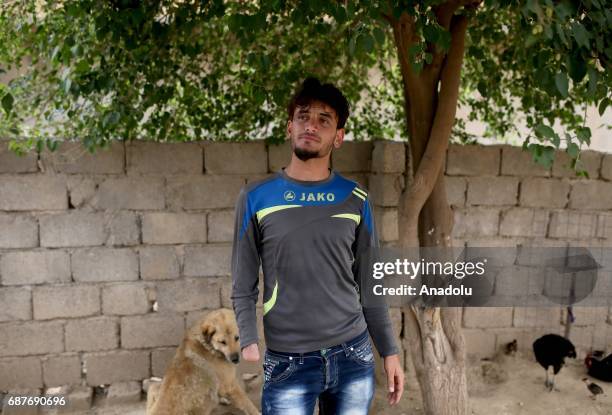 Azad, one of the two siblings who was accused of theft and whose right hand was cut off by Daesh, plays with a dog in Ninova, Iraq on May 23, 2017....