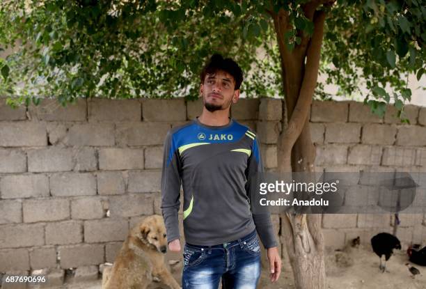 Azad, one of the two siblings who was accused of theft and whose right hand was cut off by Daesh, plays with a dog in Ninova, Iraq on May 23, 2017....