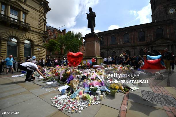 Flowers, candles and other tributes in memory of the victims of the May 22 terror attack at the Manchester Arena are piled around the statue of...