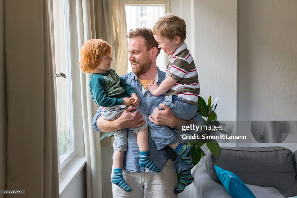 Cheerful young father holding two toddler boys