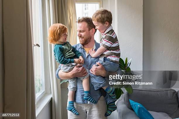 cheerful young father holding two toddler boys - leanintogether stock pictures, royalty-free photos & images
