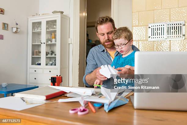 father and toddler son making paper plane at home - basteln stock-fotos und bilder