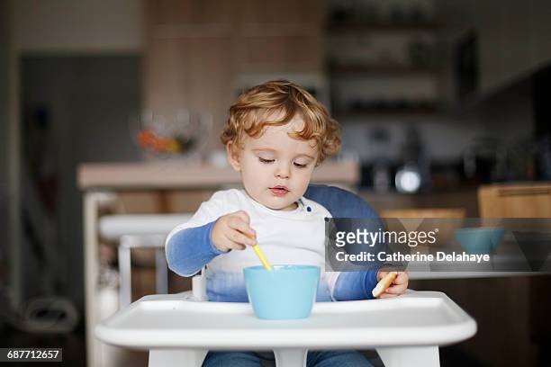 a 15 months old boy eating in his high chair - babyhood stock pictures, royalty-free photos & images