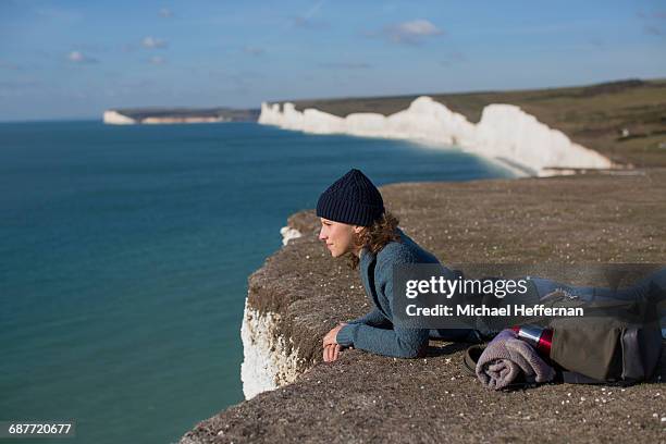 woman lying at edge of cliff - allongé sur le devant photos et images de collection