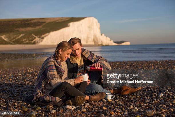 couple drinking coffee on beach - seven sisters cliffs stockfoto's en -beelden
