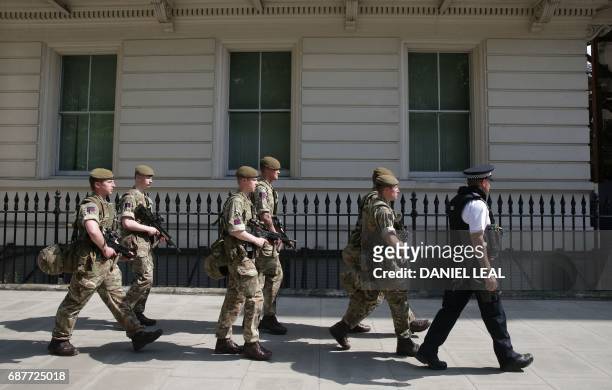 British Army soldiers are led by a police officer into a building near to Buckingham Palace in central London on May 24, 2017. - Britain deployed...