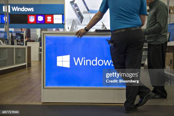 An employee assists a customer with Microsoft Corp. Windows brand computers at a Best Buy Co. Store in Downers Grove, Illinois, U.S., on Tuesday, May...