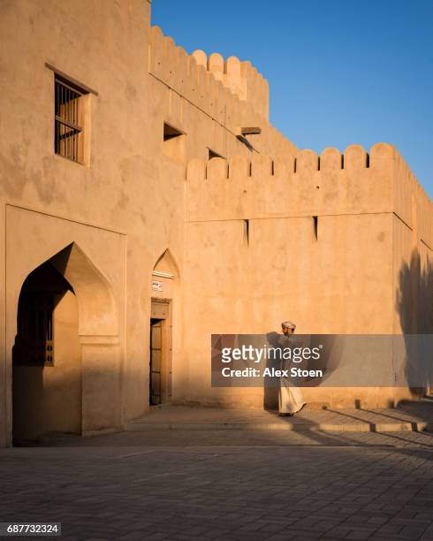 man entering arabian fort at sunset - arabic people ストックフォトと画像