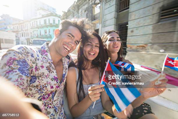 young friends sitting in car with cuban flags - havana pattern stock pictures, royalty-free photos & images