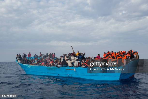 Refugees and migrants put on life jackets distributed by rescue crews of the Migrant Offshore Aid Station 'Phoenix' vessel on May 24, 2017 off...