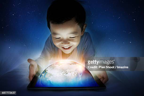 a boy looking at the earth on the tablet in the duvet - digital native stock illustrations