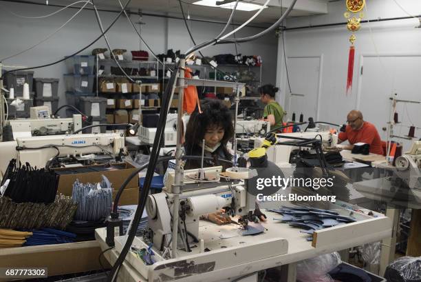 An employee sews rows of supportive stitching on the visors of baseball hats at the Graffiti Caps production facility in Cleveland, Ohio, U.S., on...