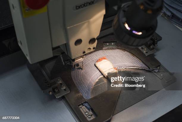 An automated sewing machine sews rows of supportive stitching on the visors of baseball hats at the Graffiti Caps production facility in Cleveland,...